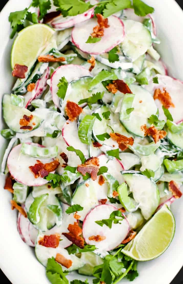 crunchy cucumber salad with bacon, in white dish overhead closeup view