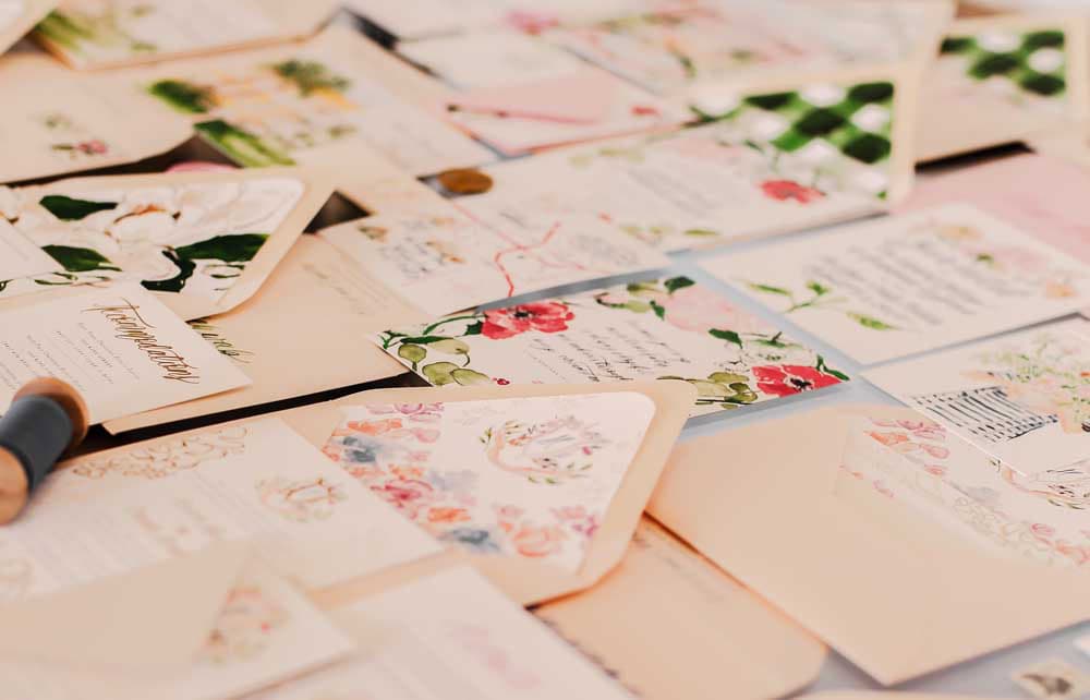a variety of invitations and envelopes on a table.