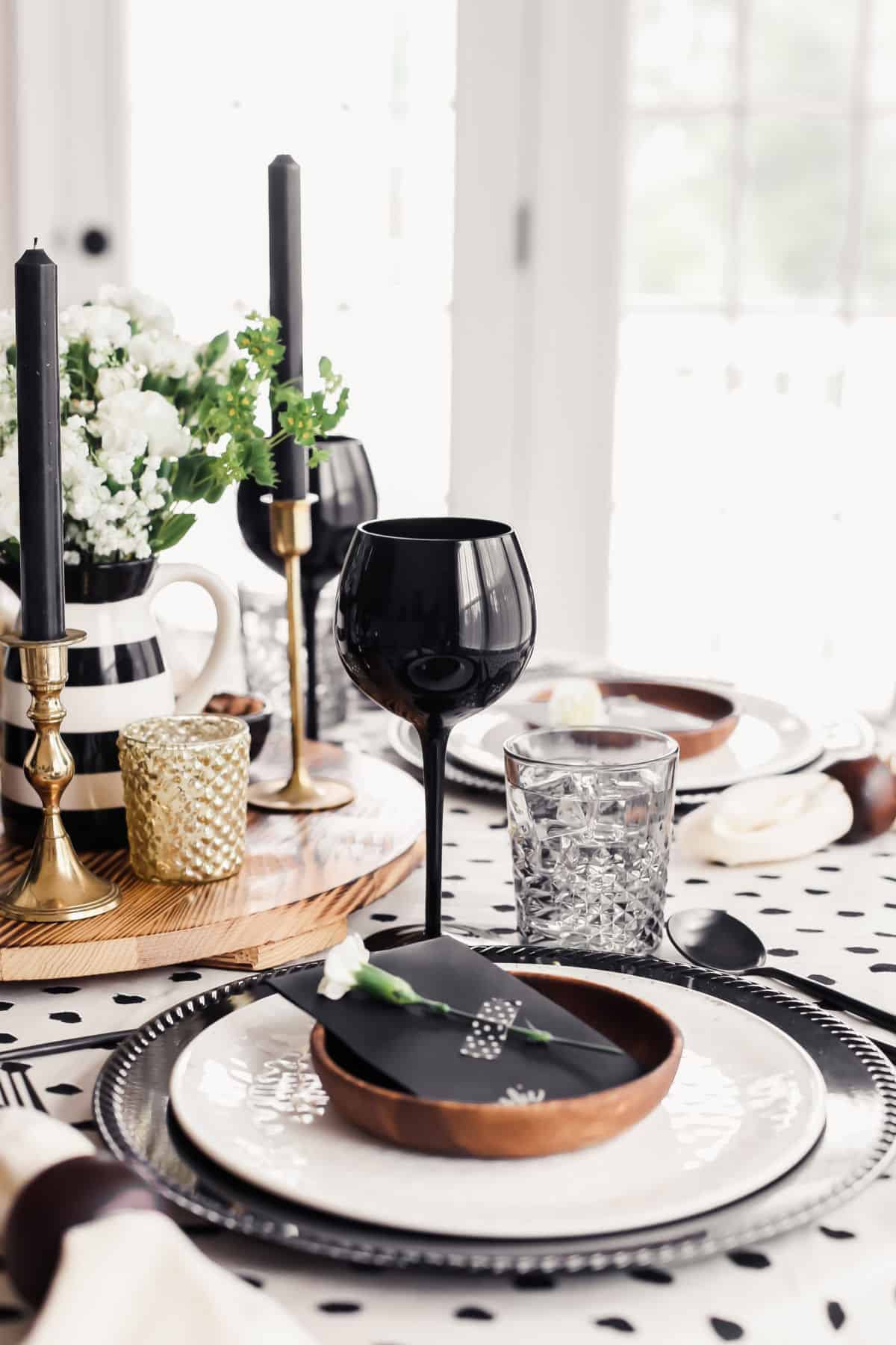 table setting with black charger, white plate, wood small plate