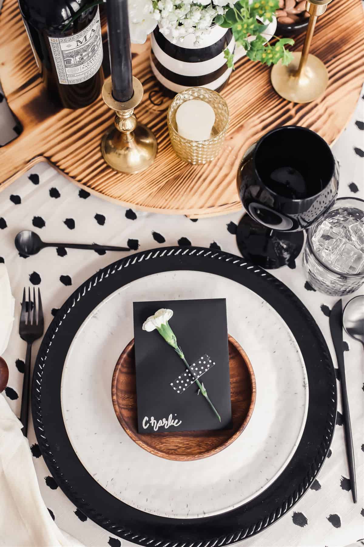 black charger, tan plate, wood small plate, black place card on table, overhead