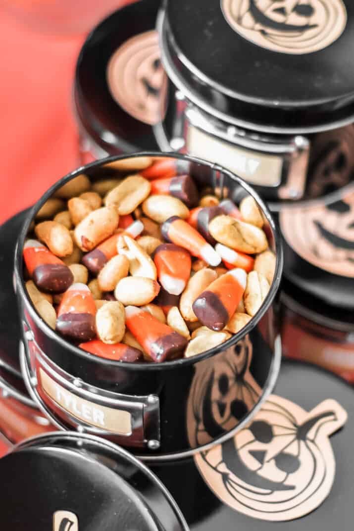 black snack tins with peanuts and candy corn inside, for Halloween