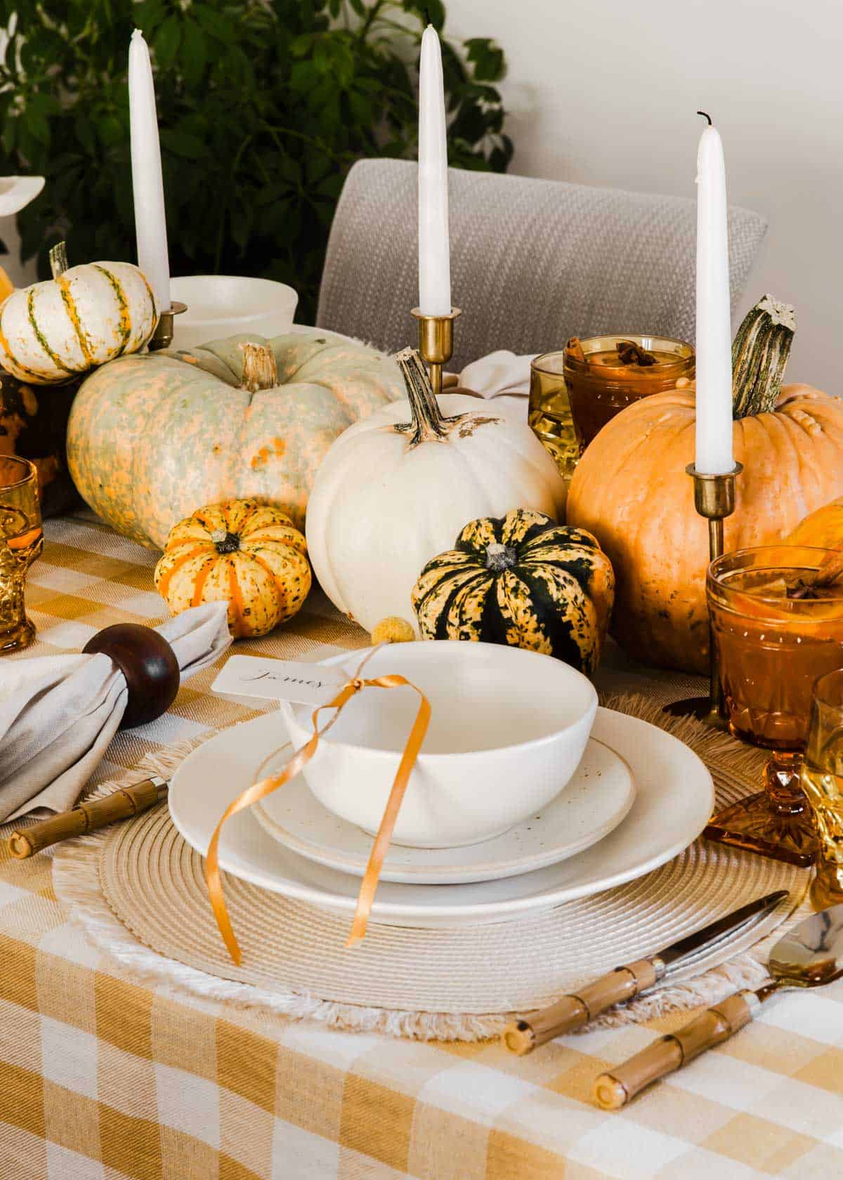 cream colored dishes and bowl on place mat on gold and white checked tablecloth.