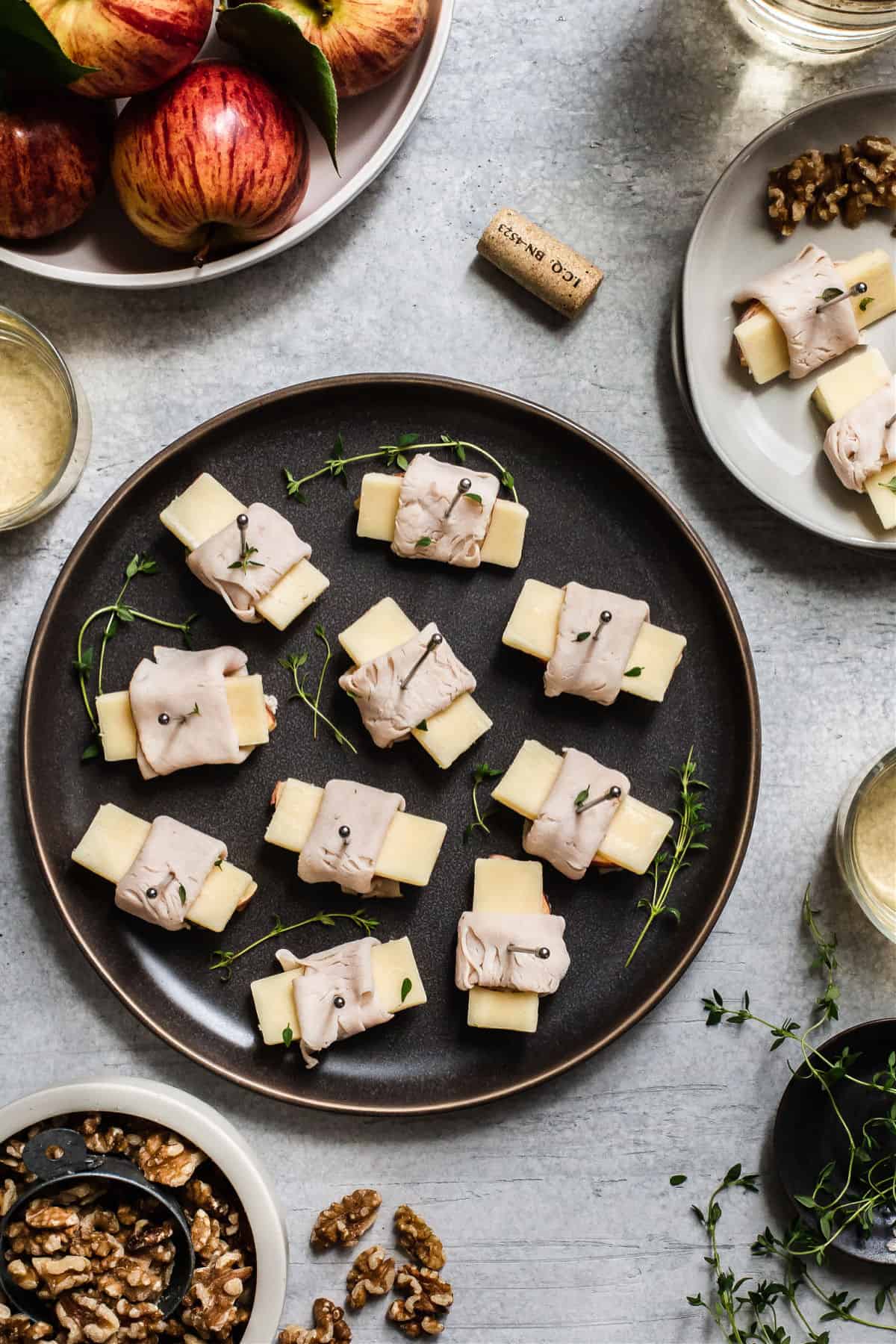 apples and cheese wrapped in deli-style turkey, on dark gray plate