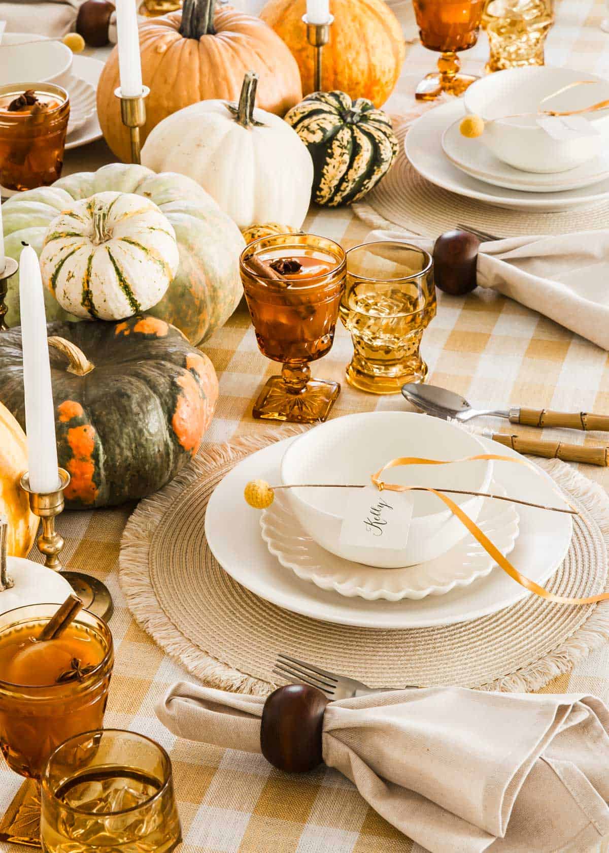 fall tablescape with yellow and cream dishes, tablecloth, and pumpkin centerpiece.