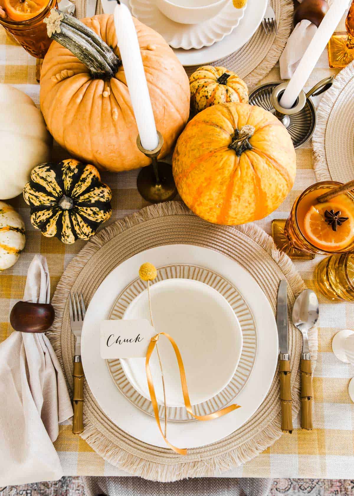 cream colored dishes and bowl on place mat on gold and white checked tablecloth.