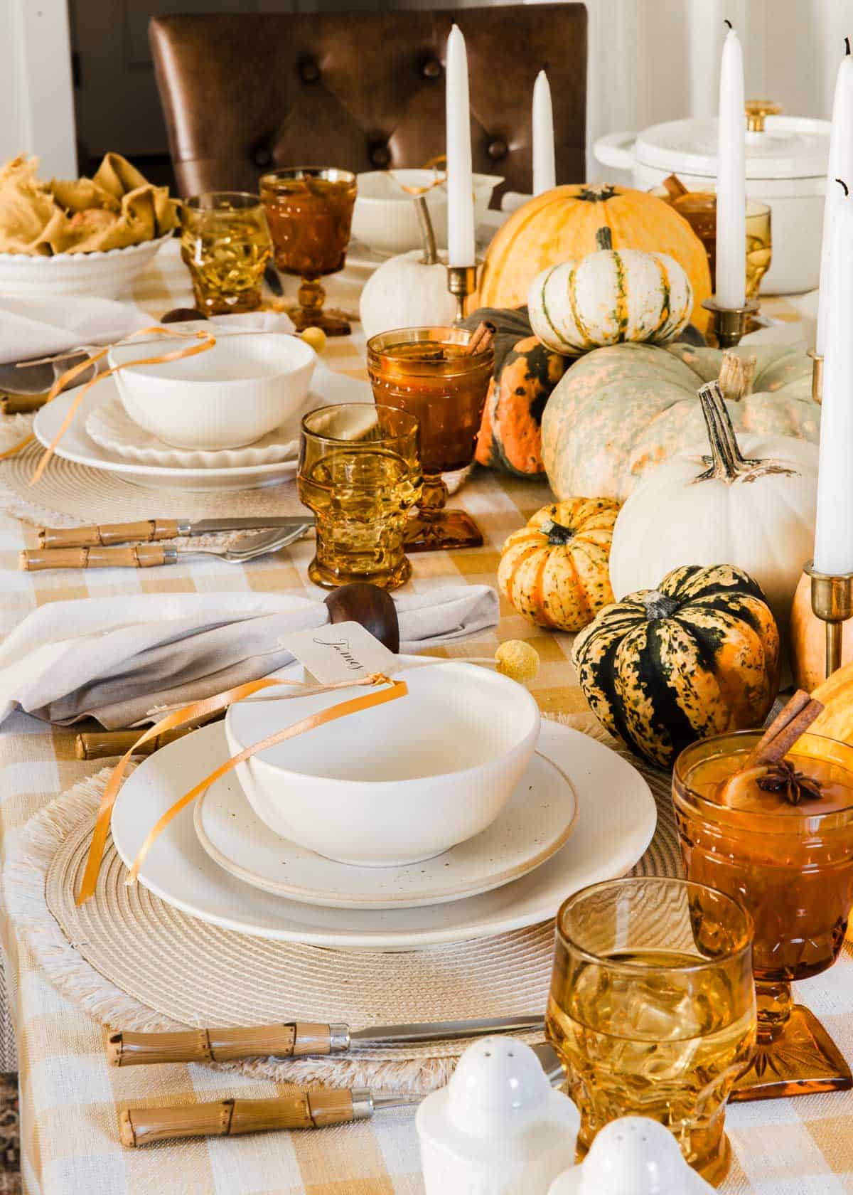 fall tablescape with yellow and cream dishes, tablecloth, and pumpkin centerpiece.