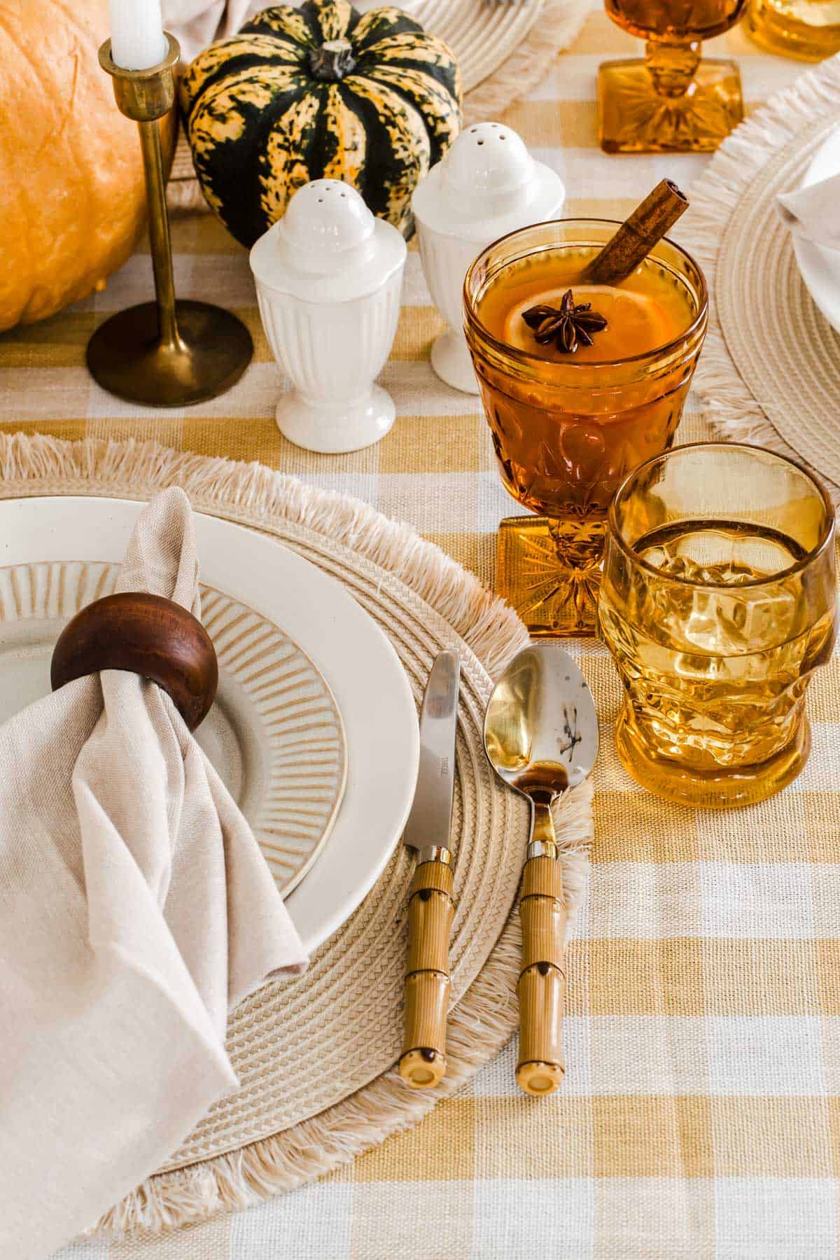 fall place setting details with amber vintage glasses, white salt and pepper shakers, and tan napkin in wood napkin ring.