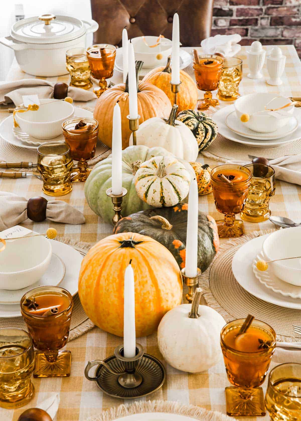 Thanksgiving table with a row of pumpkins as centerpiece, in various sizes and colors.