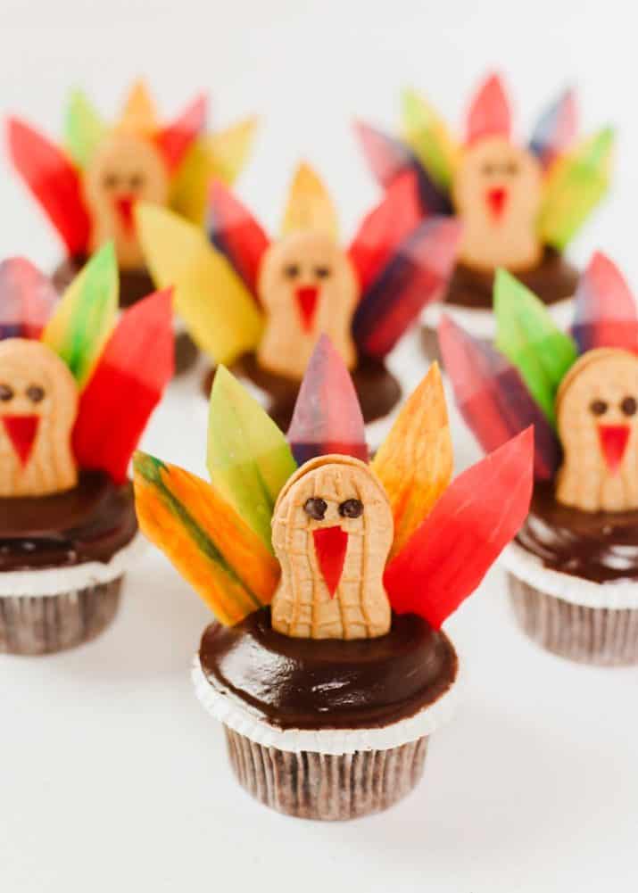 chocolate cupcakes decorated like turkeys, on white table.