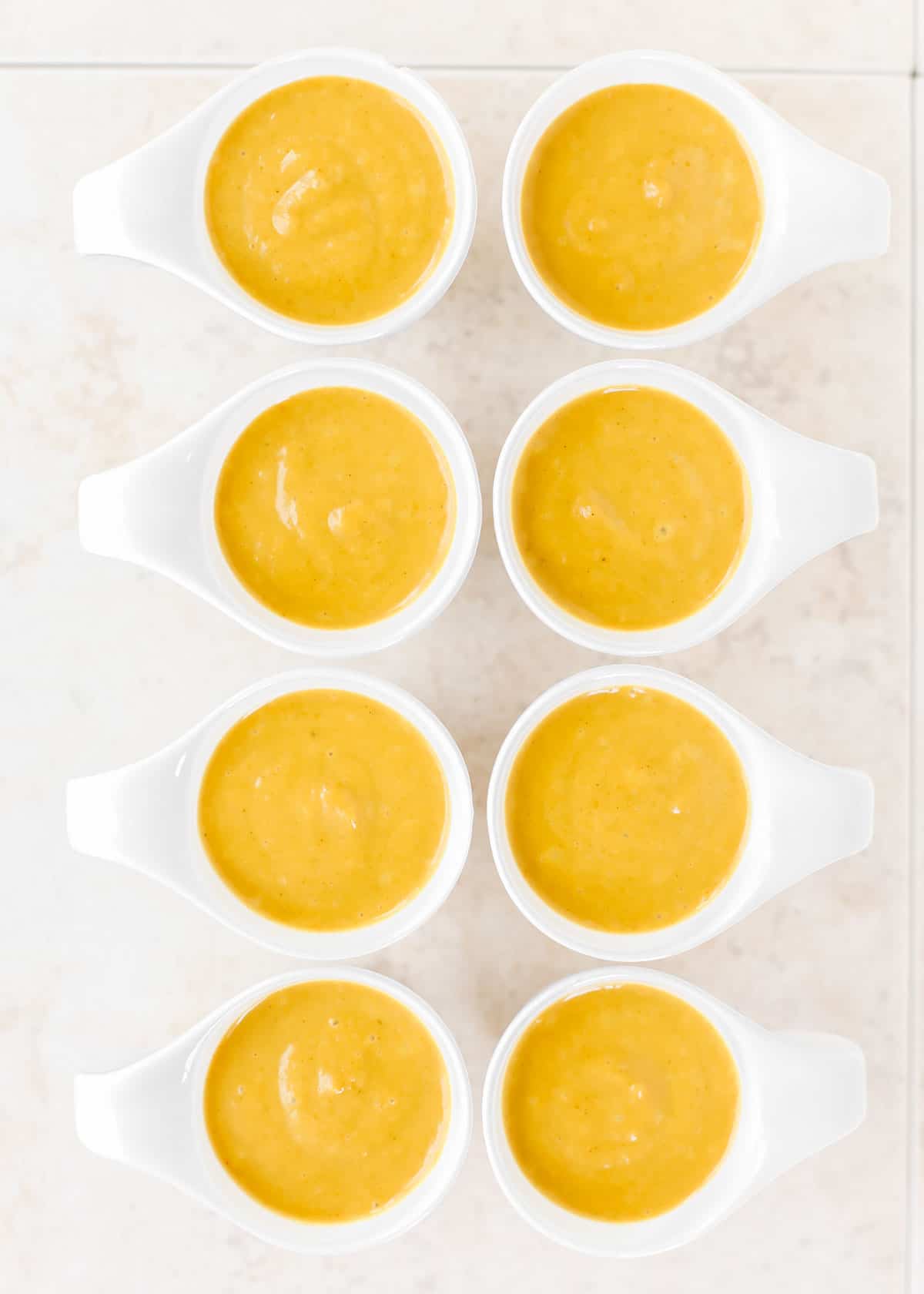 overhead view of 8 mini cups with orange soup inside.