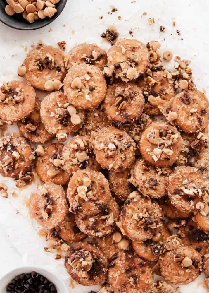pile of homemade Ritz toffee crackers topped with nuts and chocolate chips.