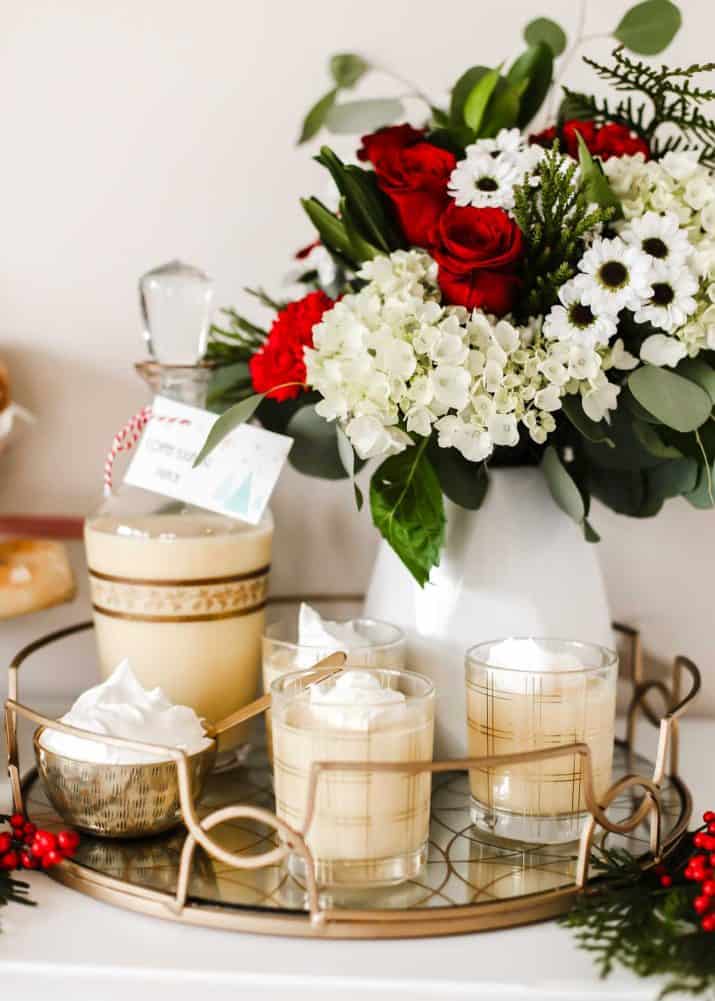 tray with eggnog in glasses and vase of flowers.