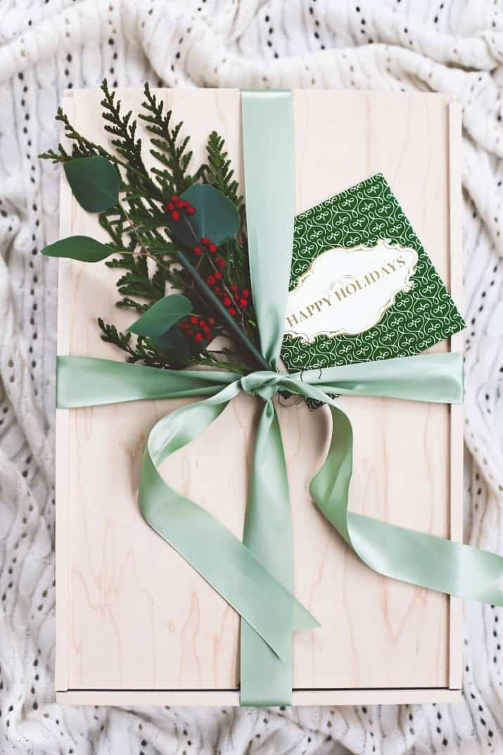 gift ideas, wooden box wrapped with green ribbon and greenery clippings