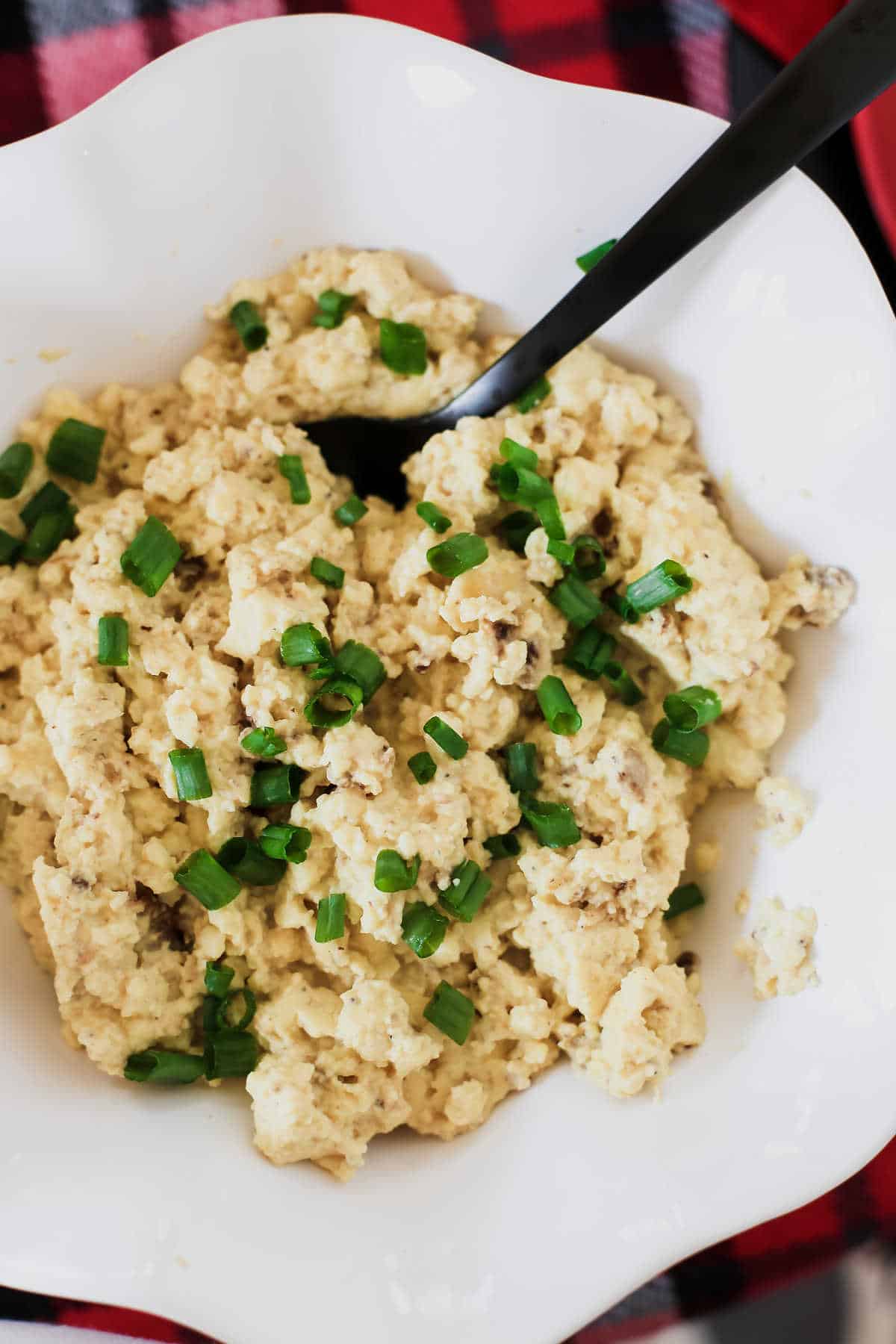 scrambled eggs sprinkled with chives, in white bowl.