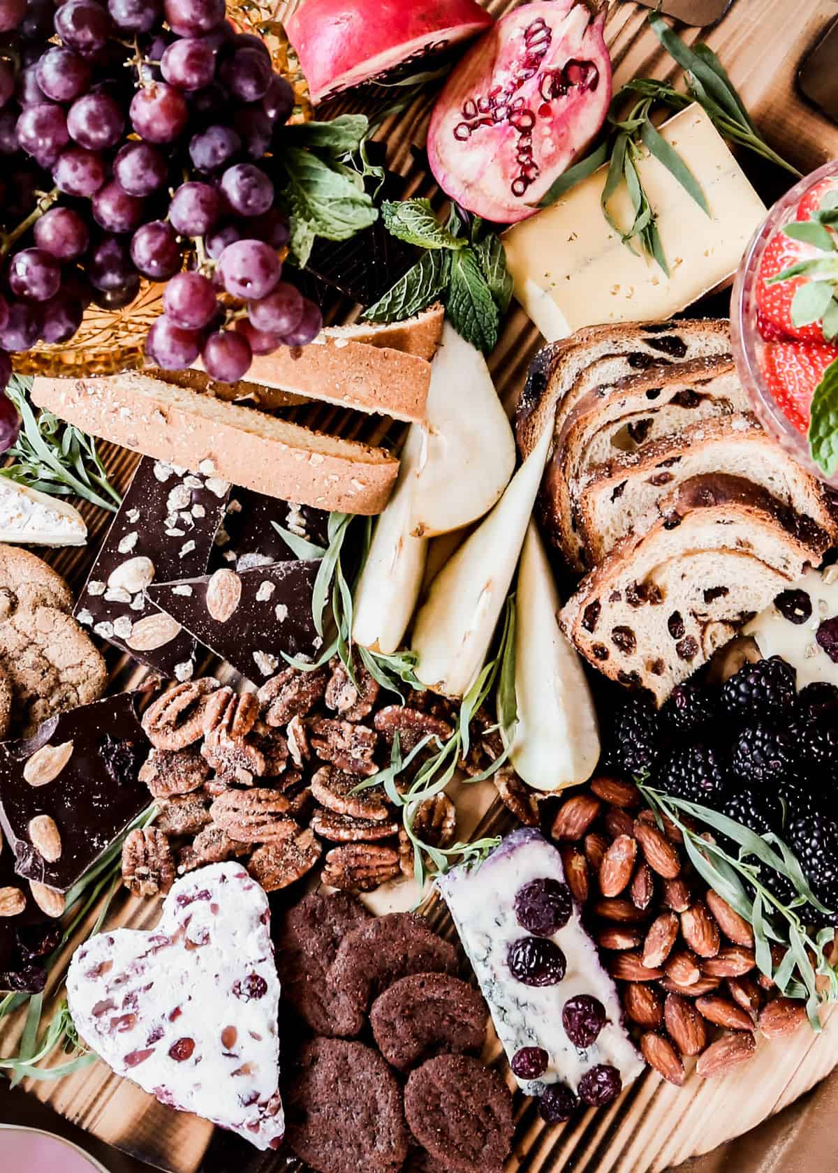 chocolate, fruit, nuts, cookies and cheese clustered on charcuterie board.