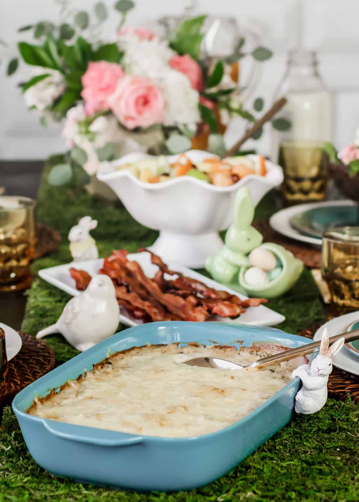 Easter table set with brunch food on green moss runner.