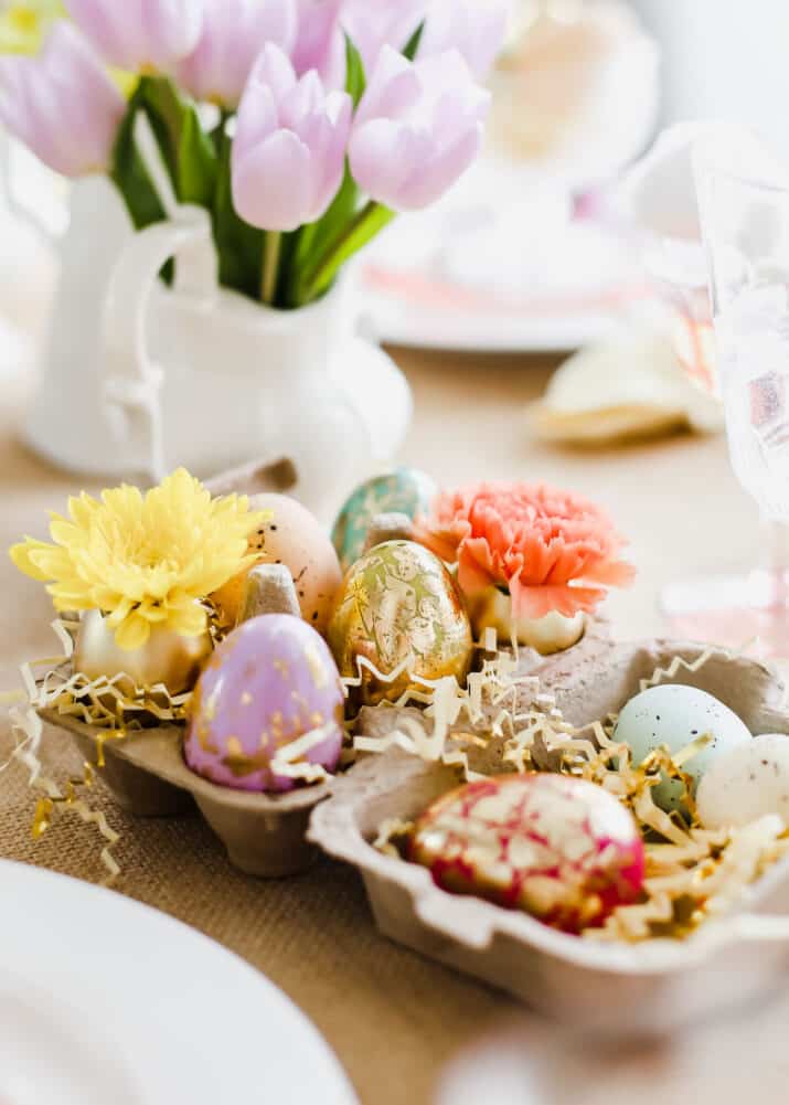 small cardboard egg carton holing decorative Easter eggs for centerpiece decor.