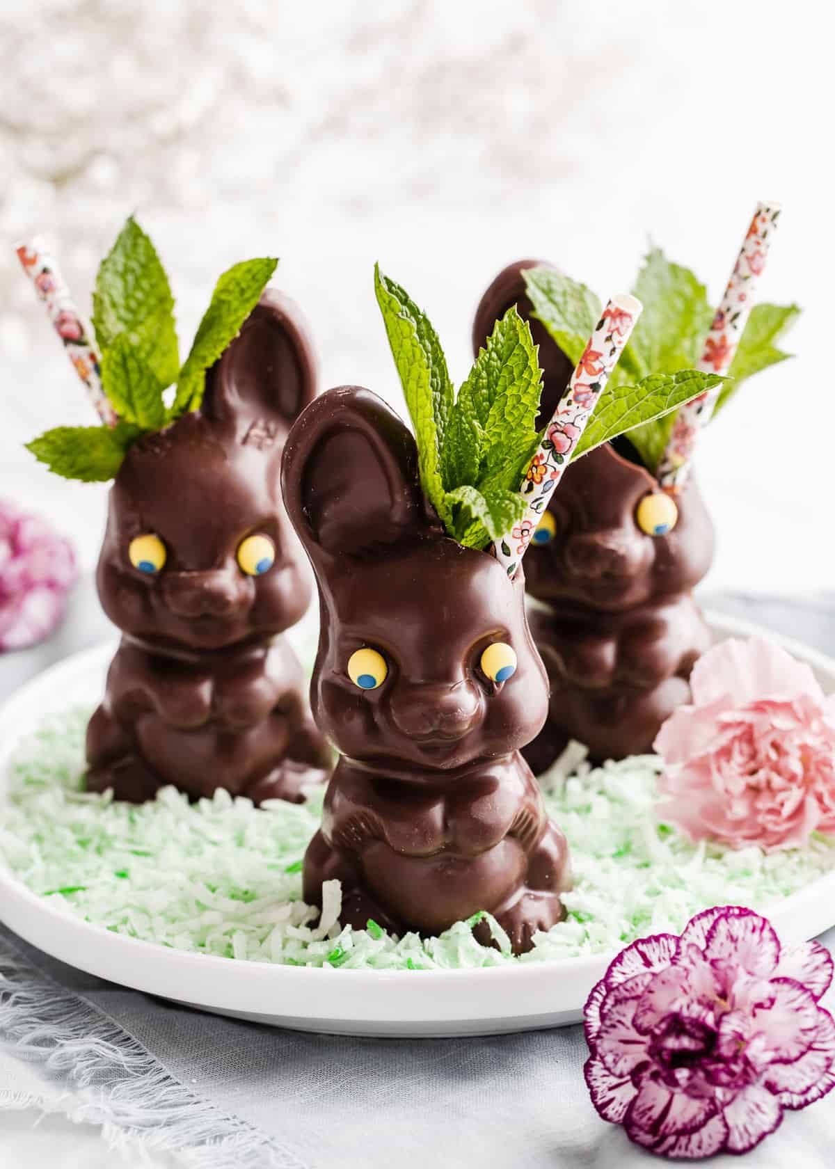 three chocolate bunnies used as drink cups with straws and mint leaves.