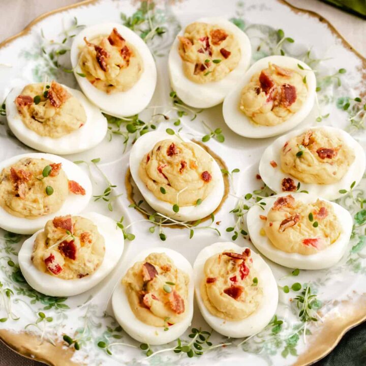 round vintage oyster plate filled with deviled eggs topped with bacon.