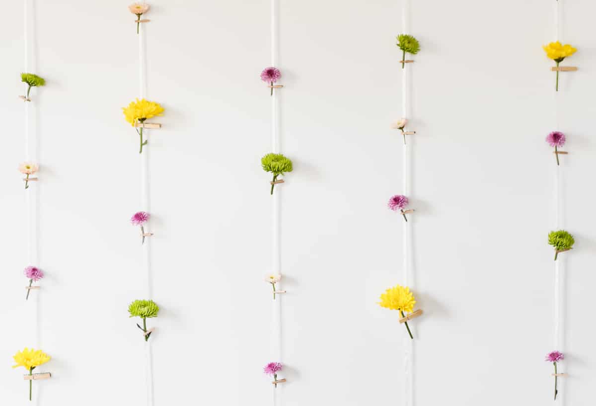 white wall with ribbons hanging with small flowers attached.