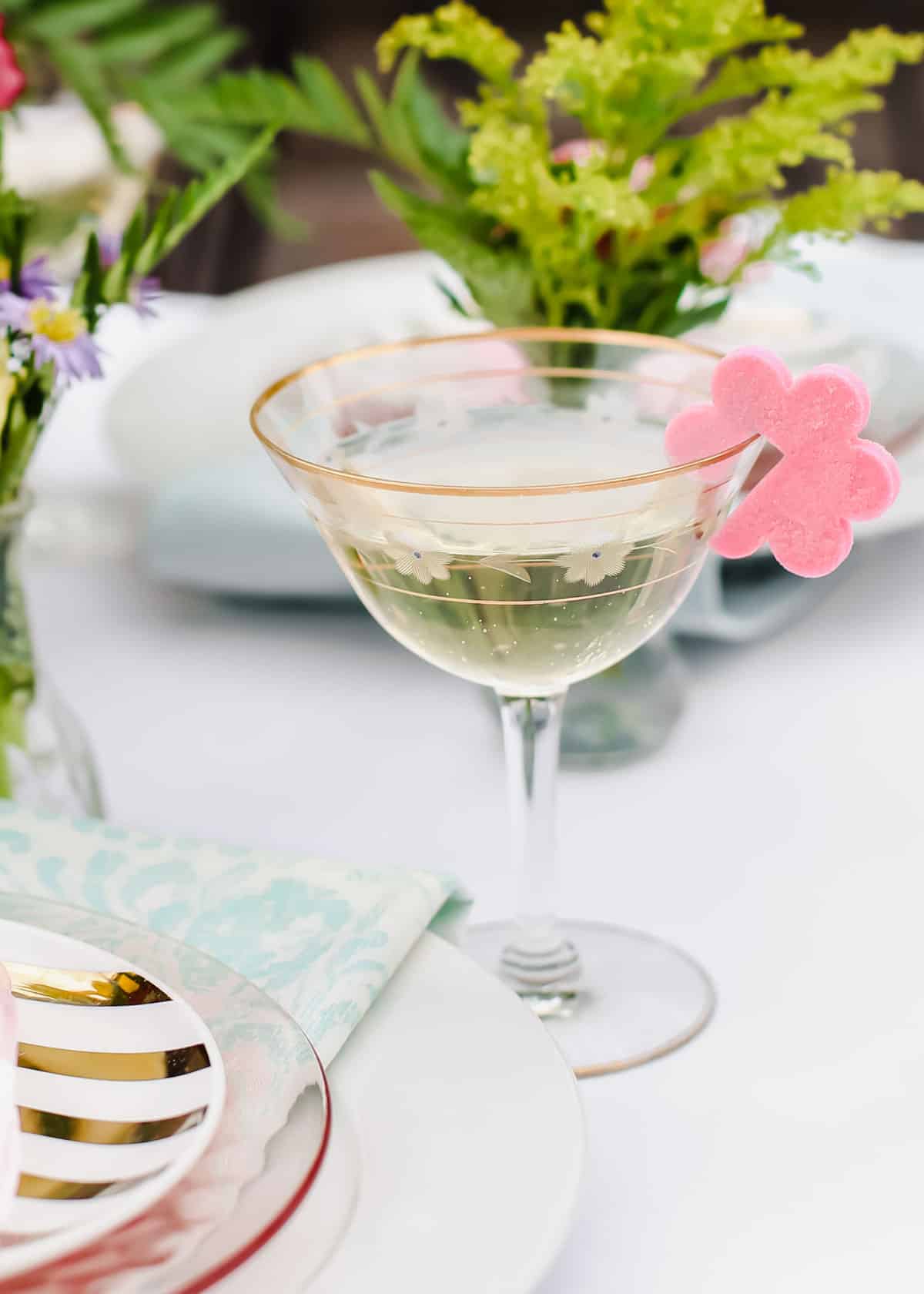 champagne in vintage coupe glass with flower shaped sugar cube hanging on side.