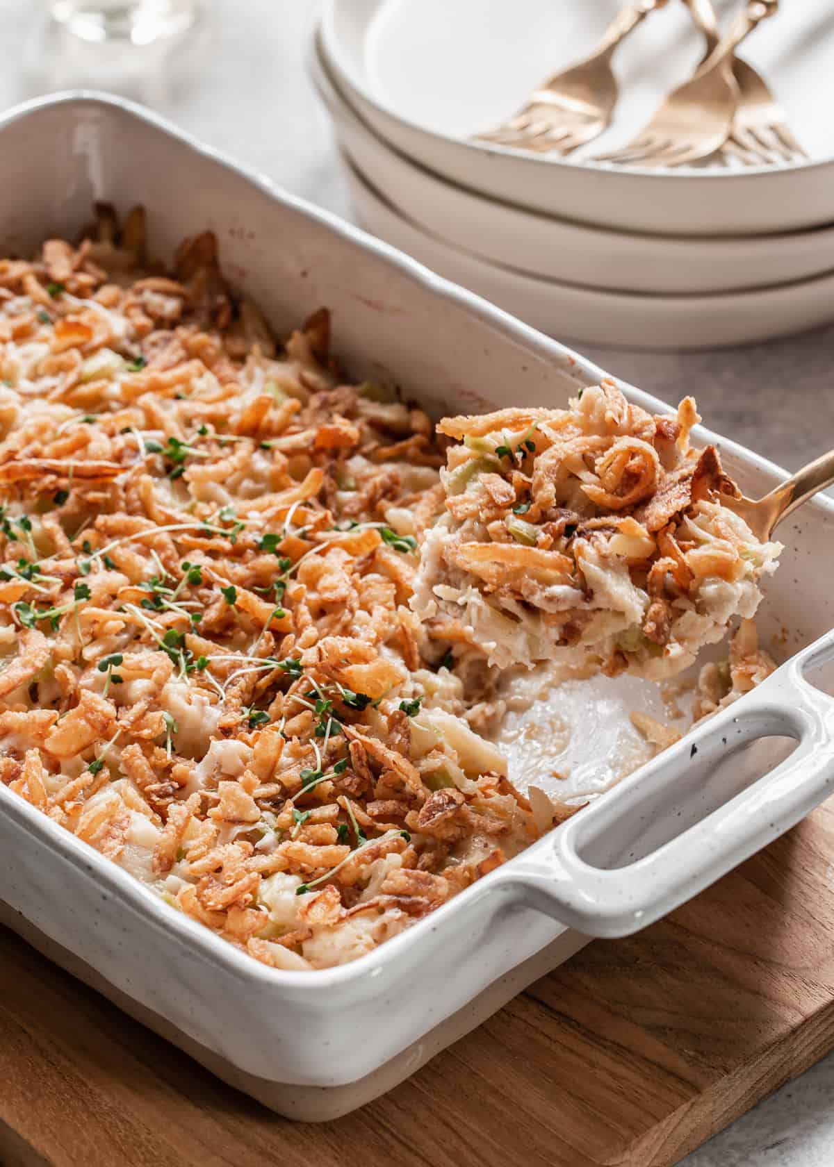 casserole topped with crunchy onions with spoon taking a scoop out of white dish.