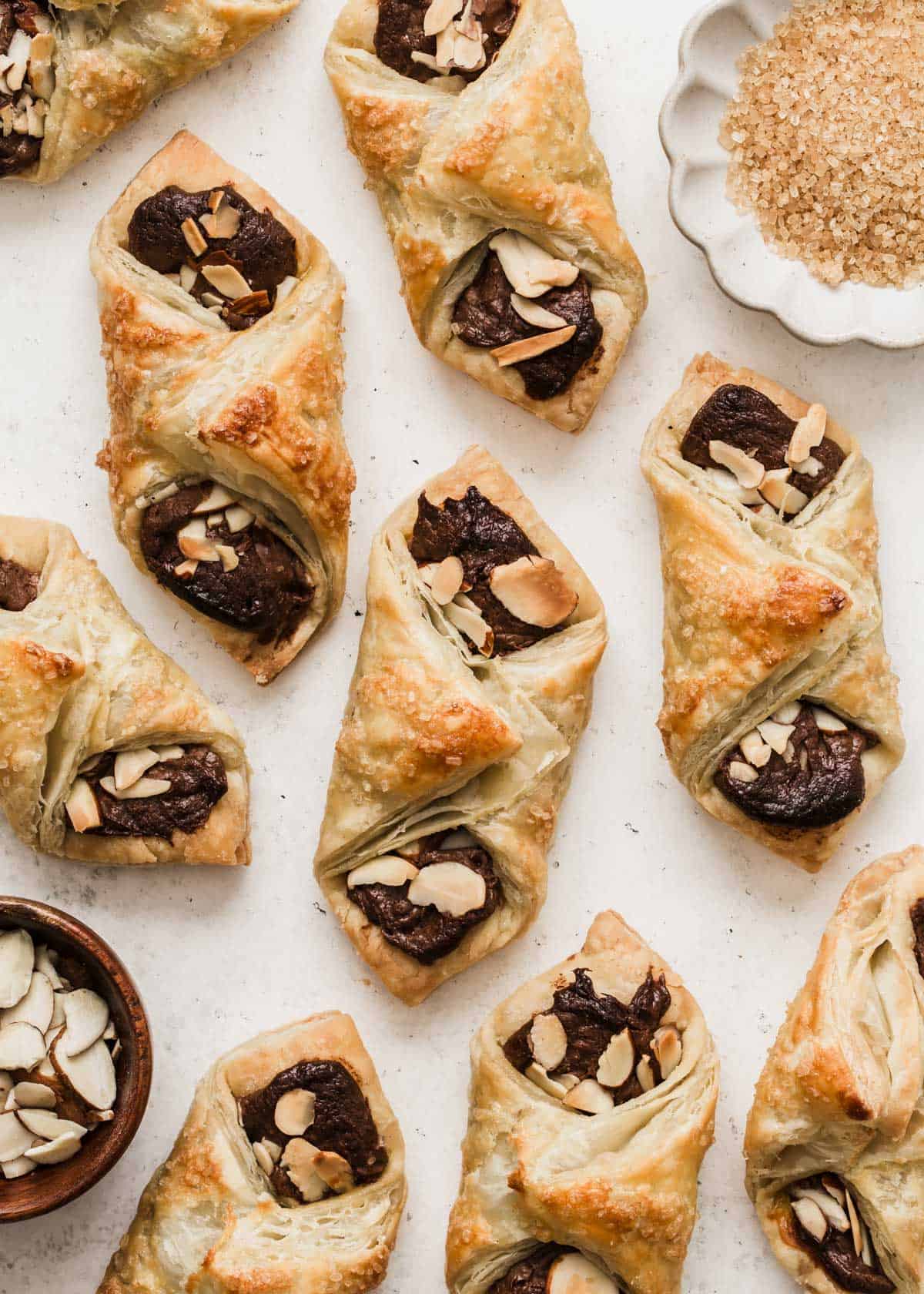 puff pastry packets with chocolate and almonds on white background.