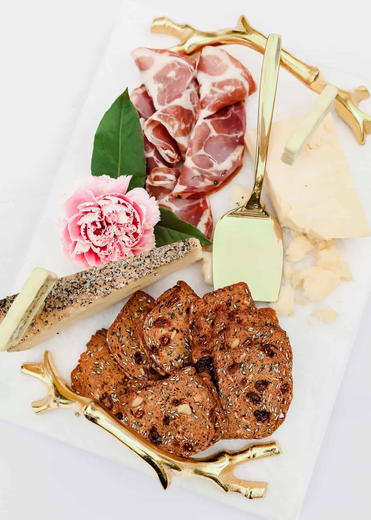 white marble platter with cured meat, cheese and crisp crackers.