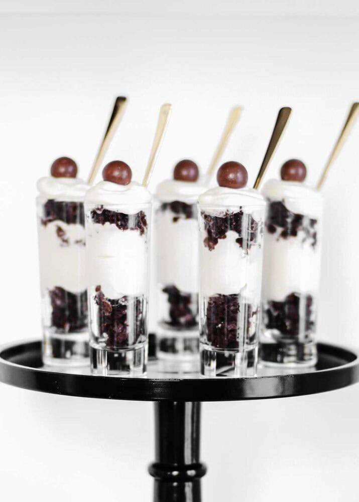 black and white dessert parfaits in mini glasses, on black cake pedestal. 