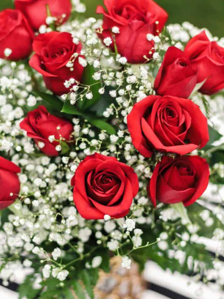 red roses and babies breath in vase on table.