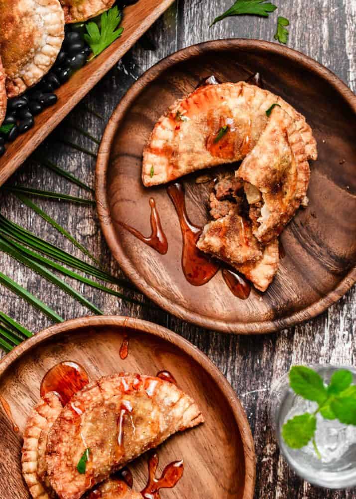 two small wood plates holding empanadas. 