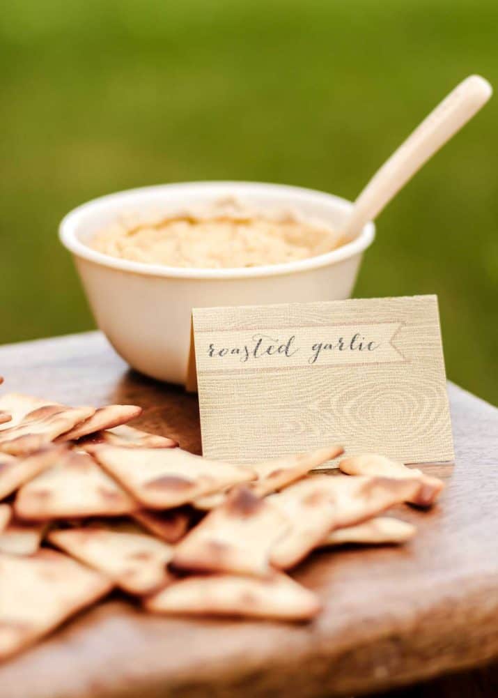 hummus in small bowl with pita crisps on the side.