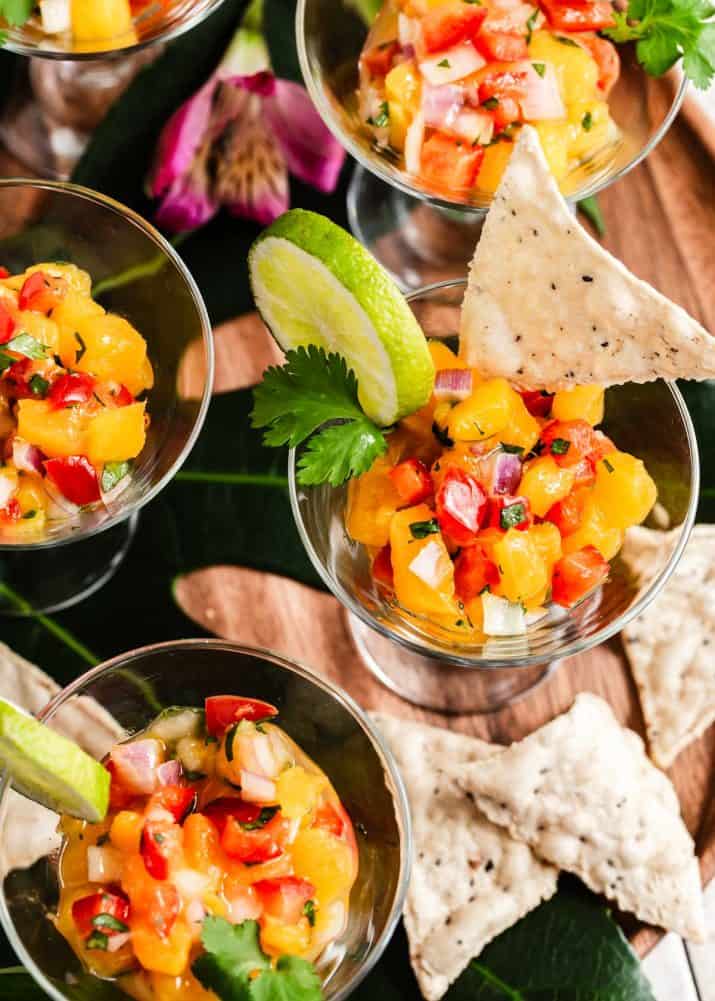 mini glasses of mango salsa with tortilla chips on the side.