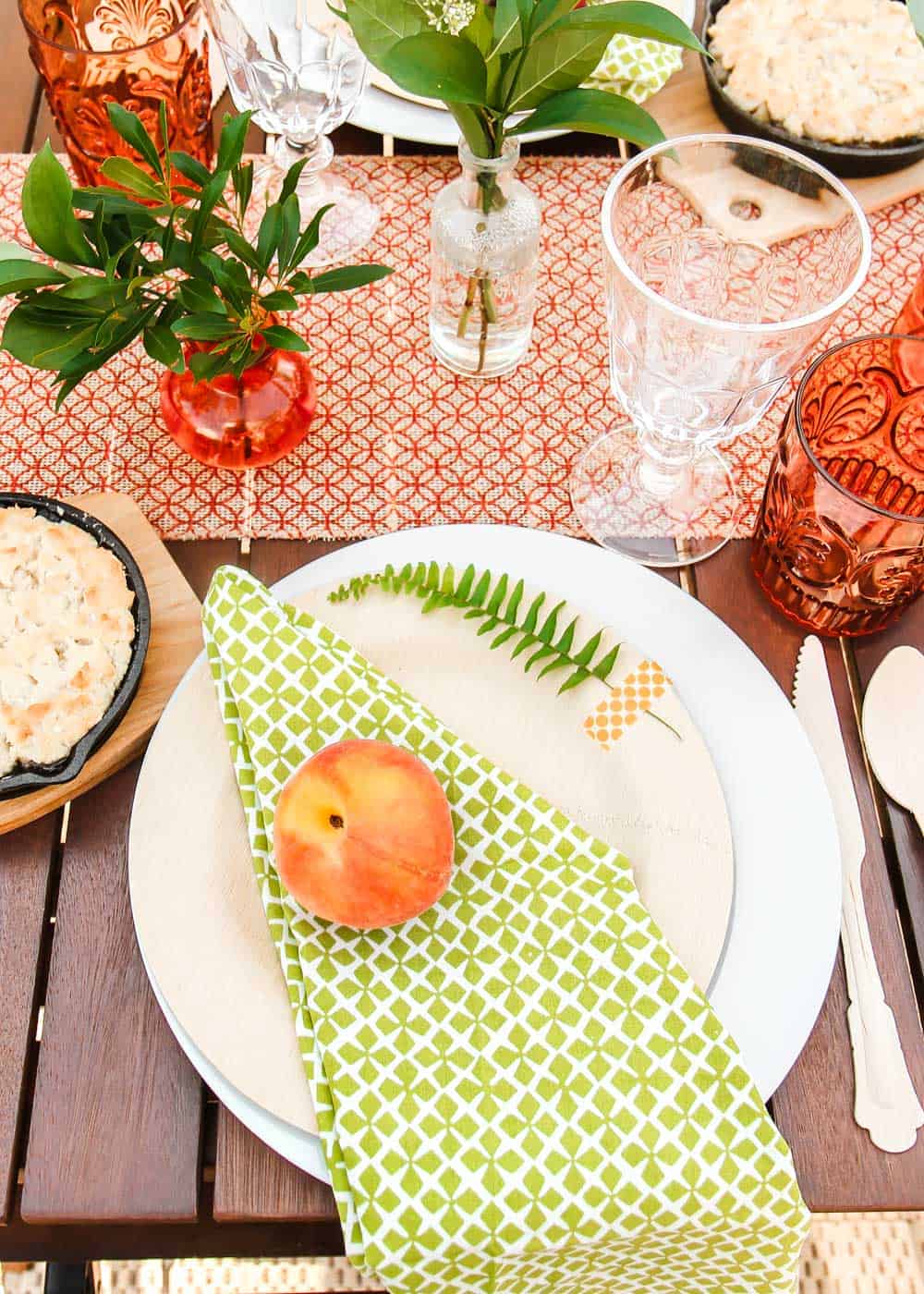 peach theme tablescape place setting with fresh peach on green napkin.