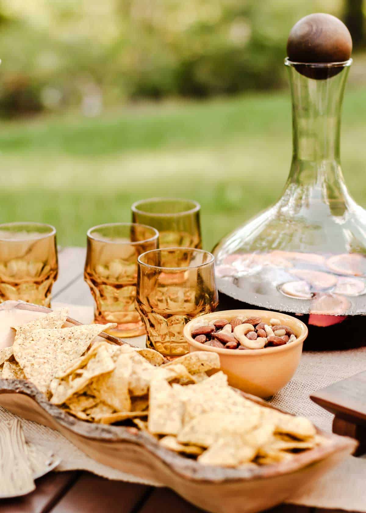 outdoor table with large carafe of sangria, glasses, and bowl of chips.