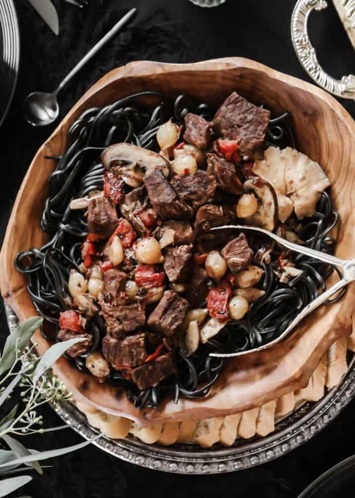 beef tips with mushrooms and onions in a wooden bowl.