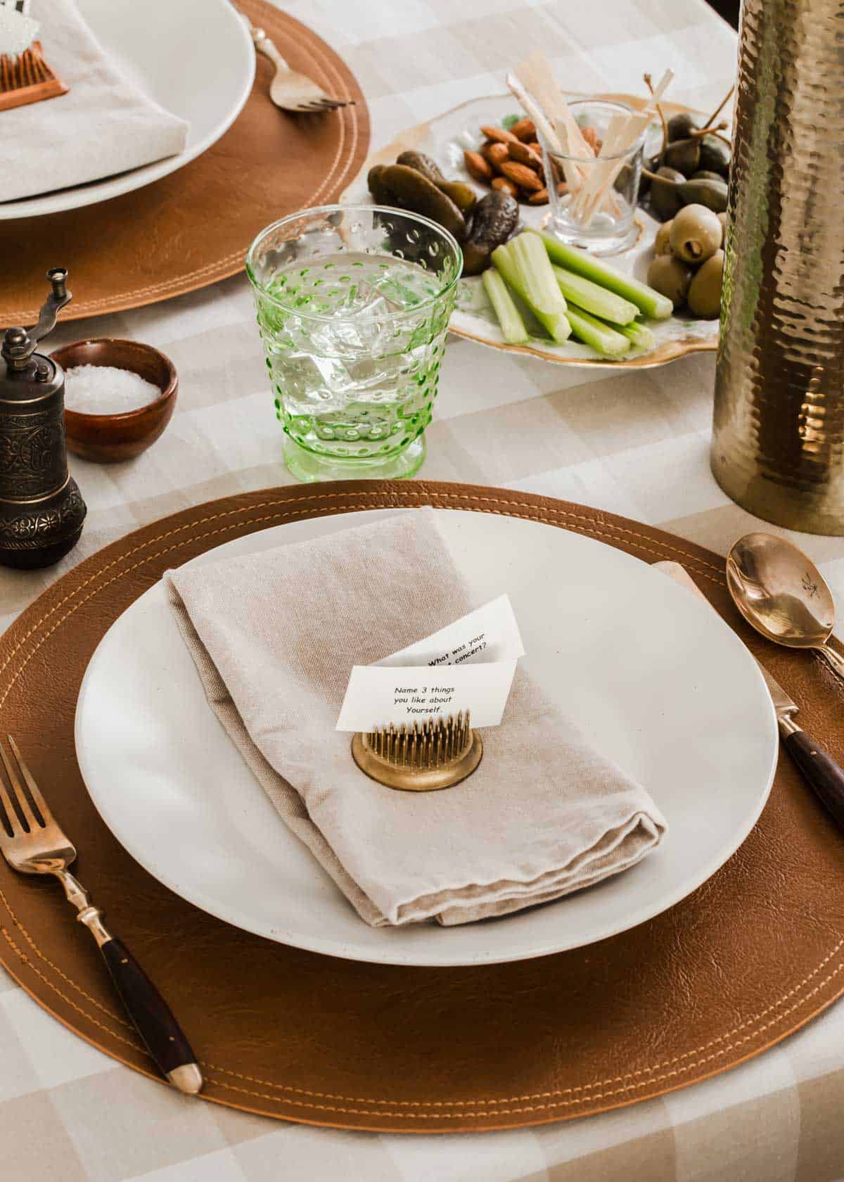 dinner table place setting with round place mat, white plate, napkin, and conversation cards on top.