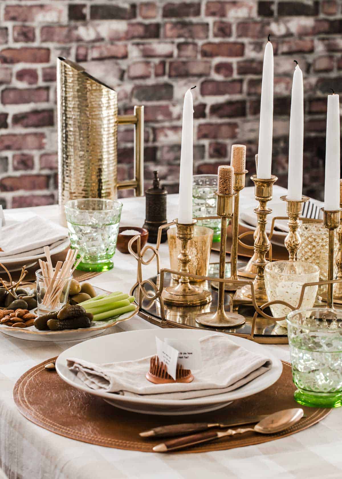 casual dinner table setting with gold candlesticks, white plates, and leather place mats.