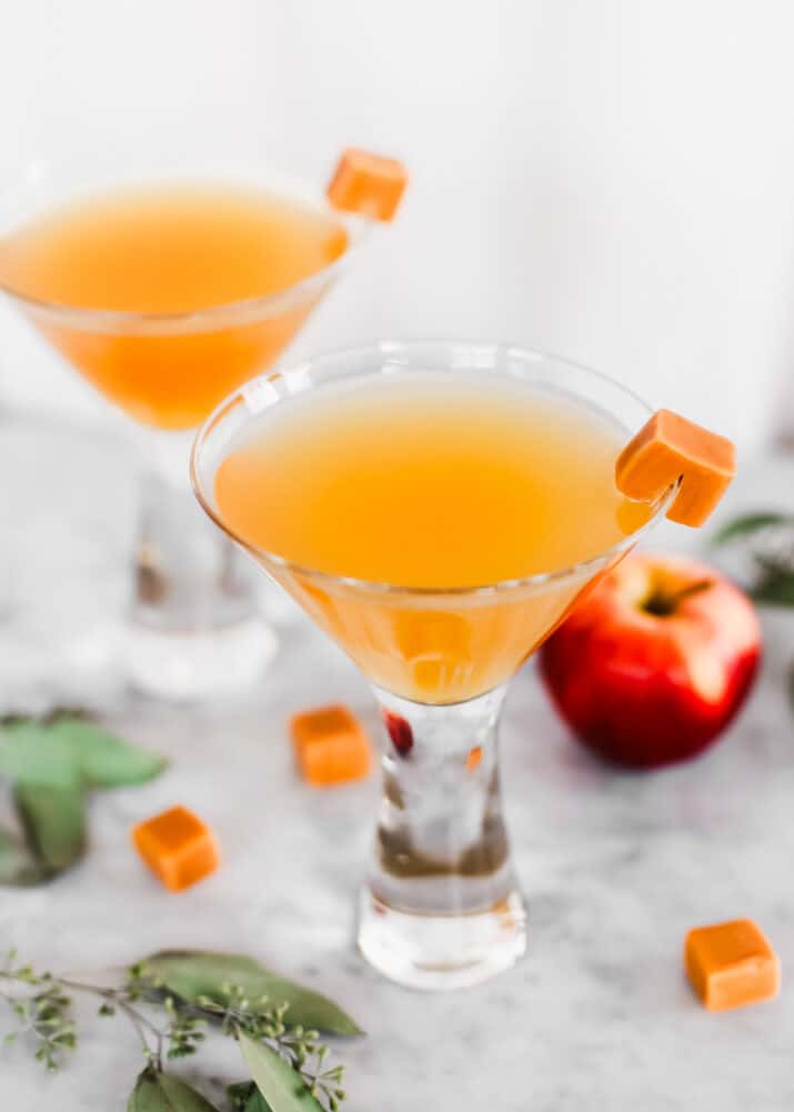 two martini glasses filled with drink and garnished with square caramel candy.