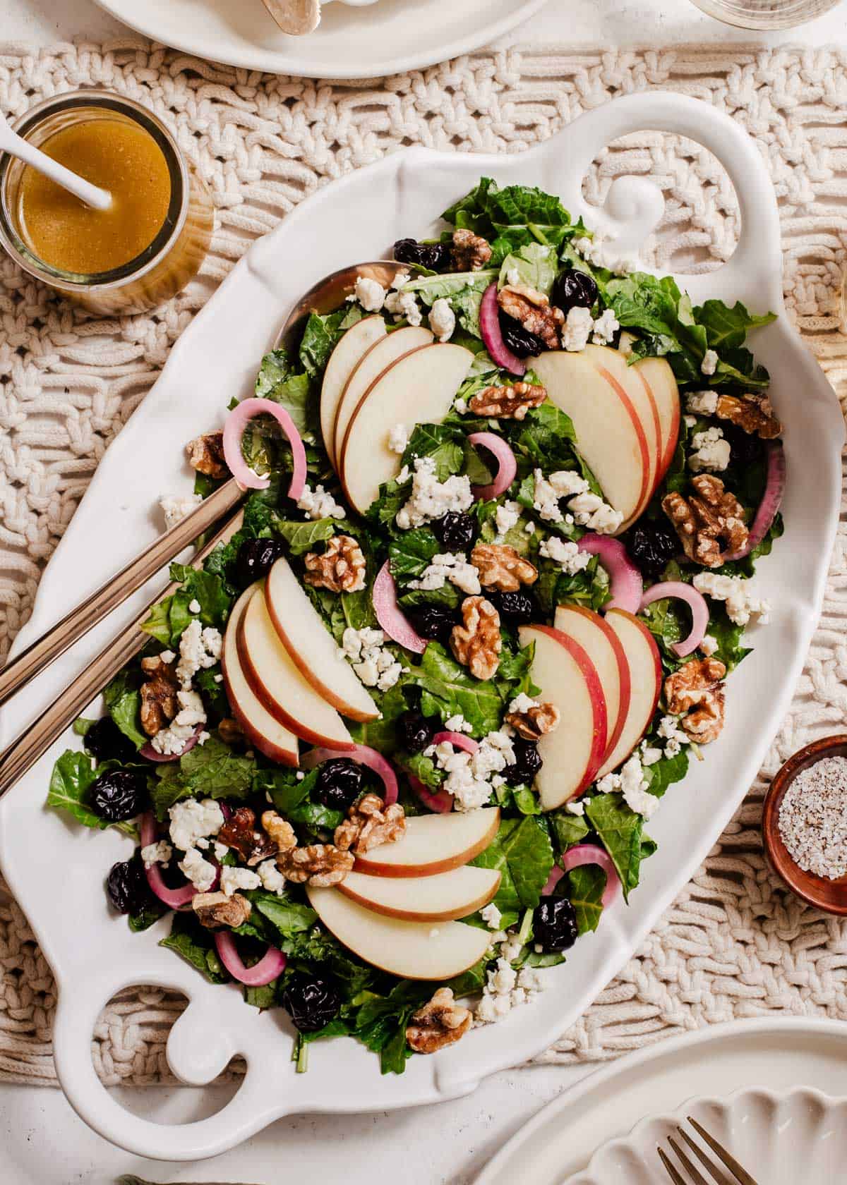 kale salad with sliced apples with dressing on the side on dinner table.