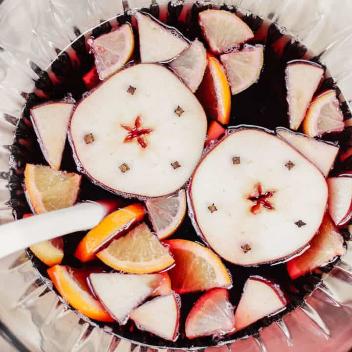 red sangria in punch bowl with apple slices and orange slices, overhead.