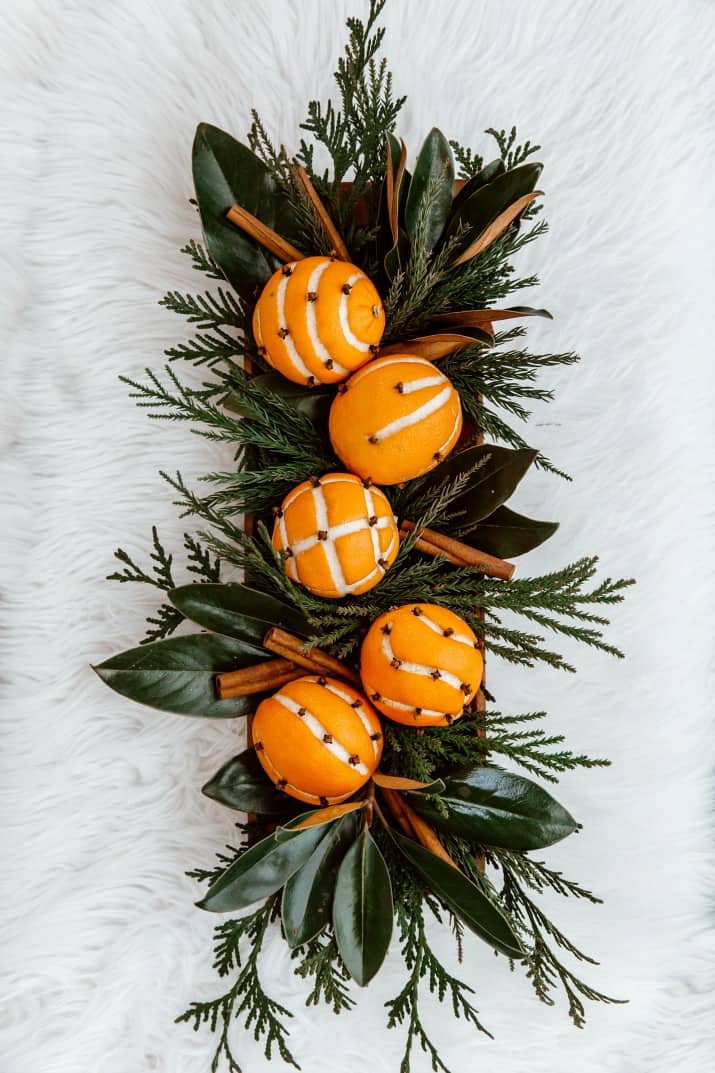 orange pomanders in wood bowl with greenery