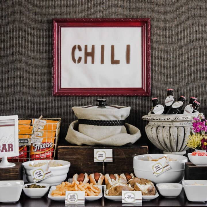 chili bar party setup with slow cooker, toppings and chili sign.