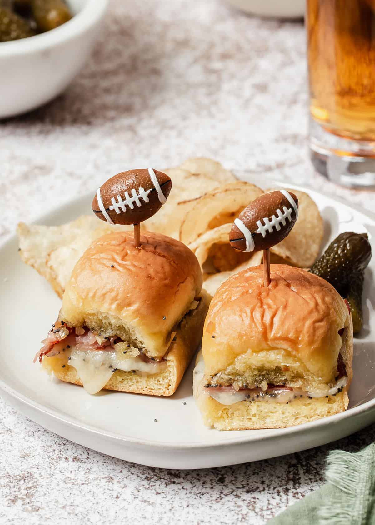 mini ham and swiss cheese sandwiches with football picks on top.