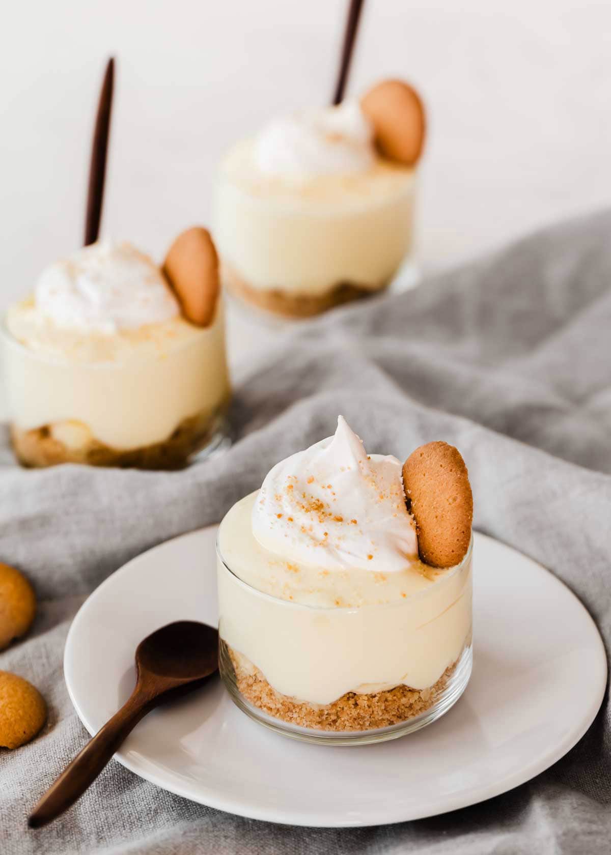 Three individual glass cups with banana pudding, sitting on gray napkin.