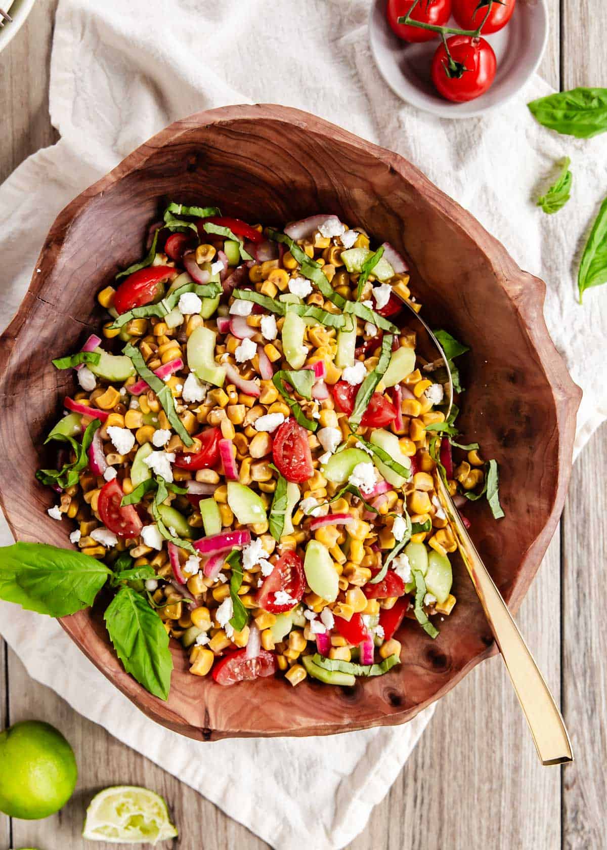 corn salad in wood bowl, garnished with fresh basil.