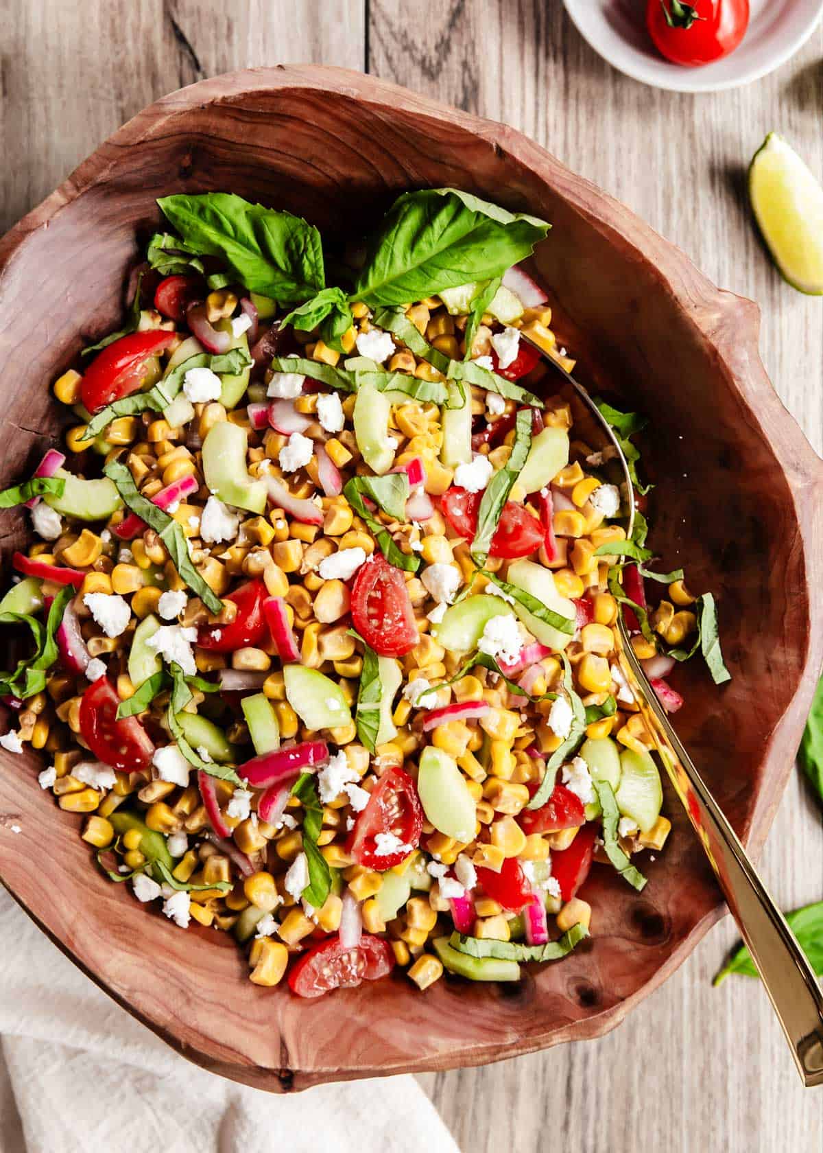 corn salad in wood bowl, garnished with fresh basil.