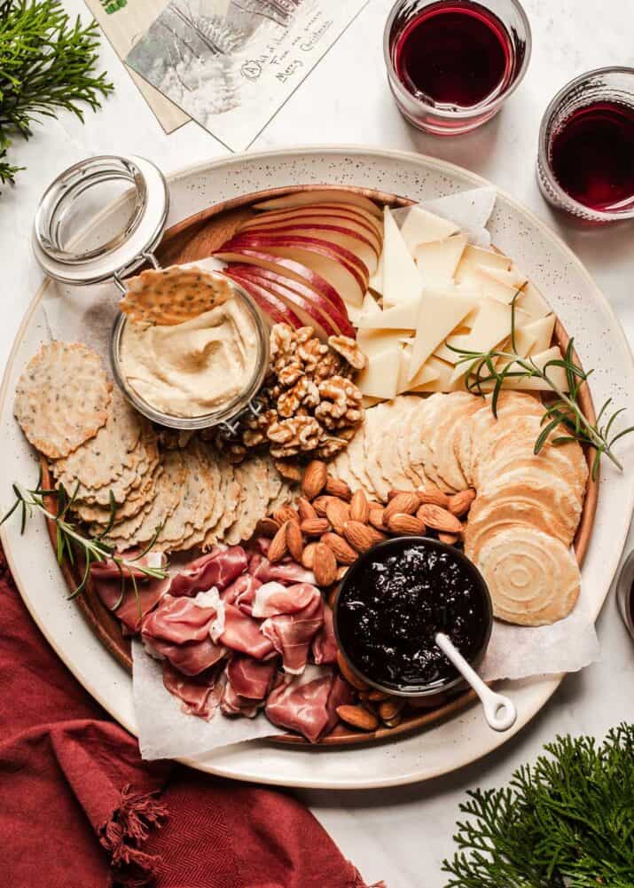 charcuterie-board on a round platter, with wine on the side.