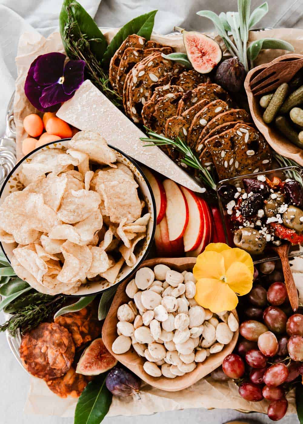 close up of charcuterie board items with chips, nuts, meat, cheese, fruit and olives.