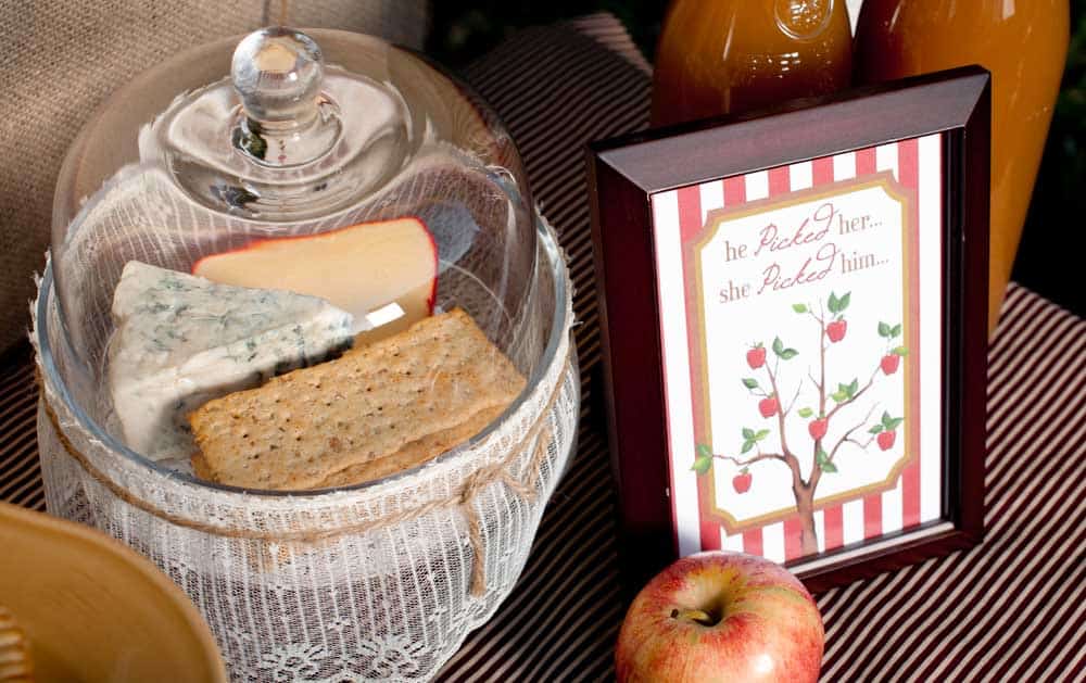 glass cloche with cheese and crackers inside, and apple themed sign.